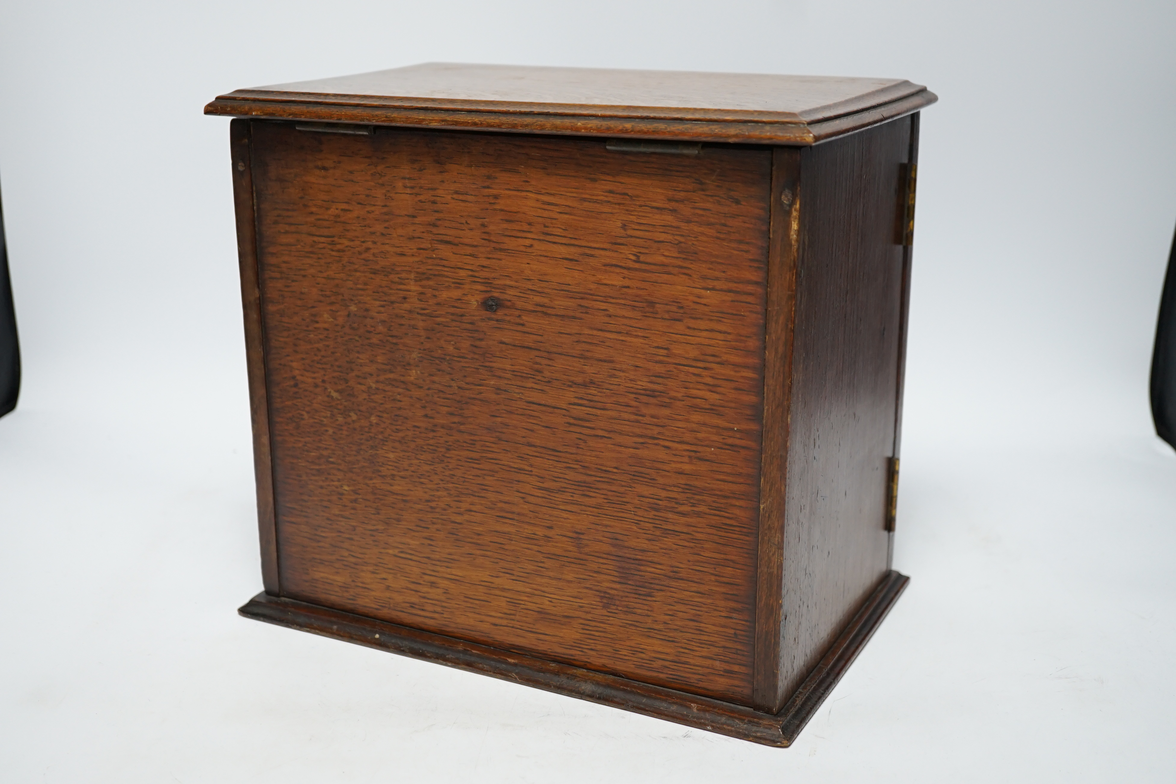 A carved oak smoker's compendium and accessories including cased cheroot holders, 25cm high